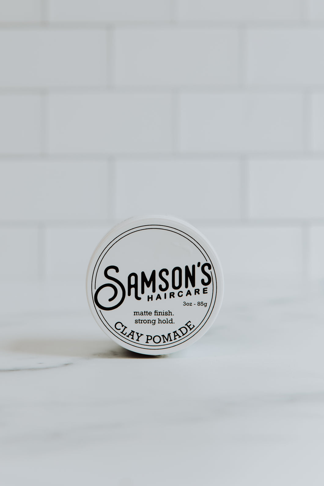 3 oz Matte Finish Clay Pomade container lying on its side, showcasing the top lid.
