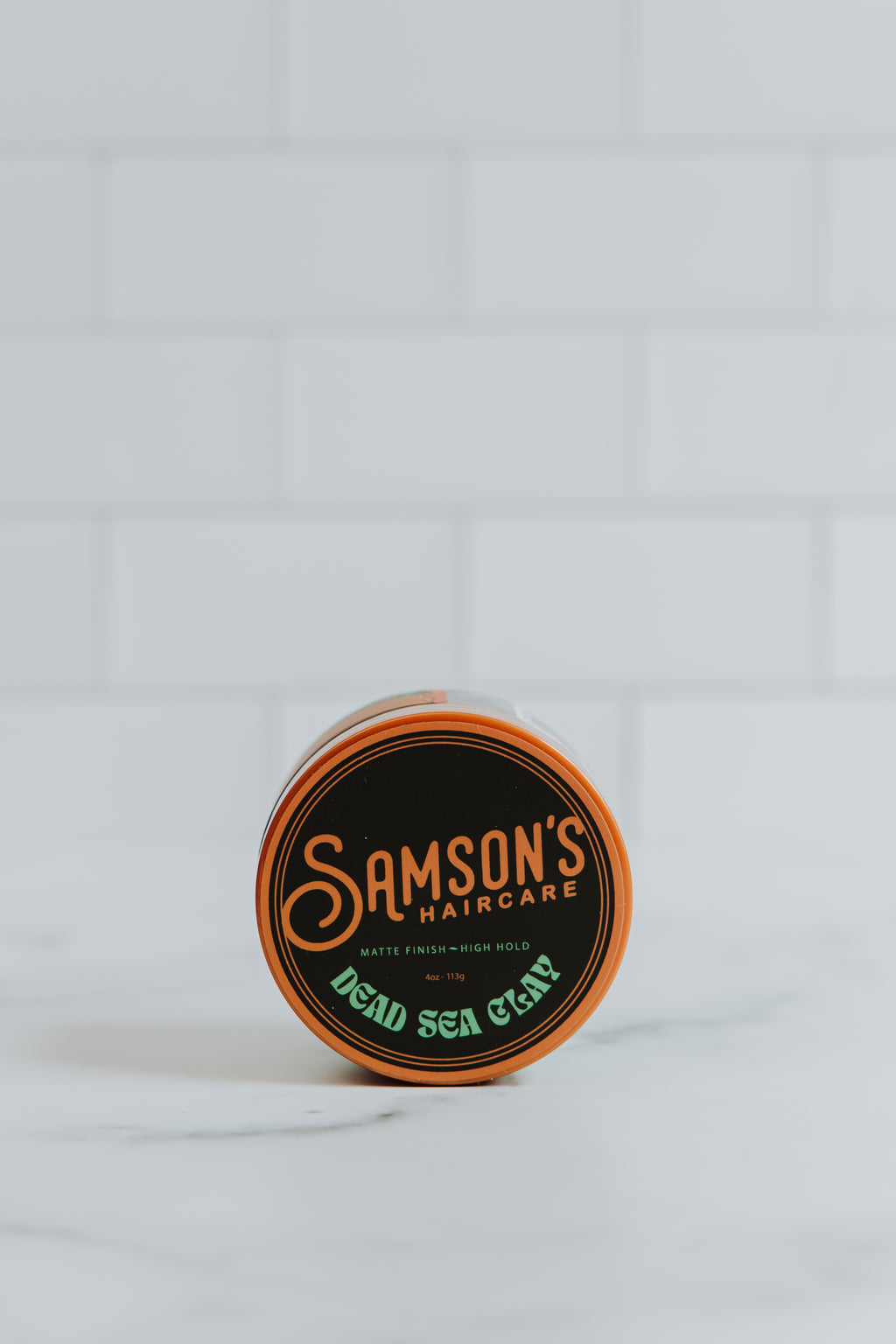 4 oz Dead Sea Clay on its side to showcase the top of the container against a white background.