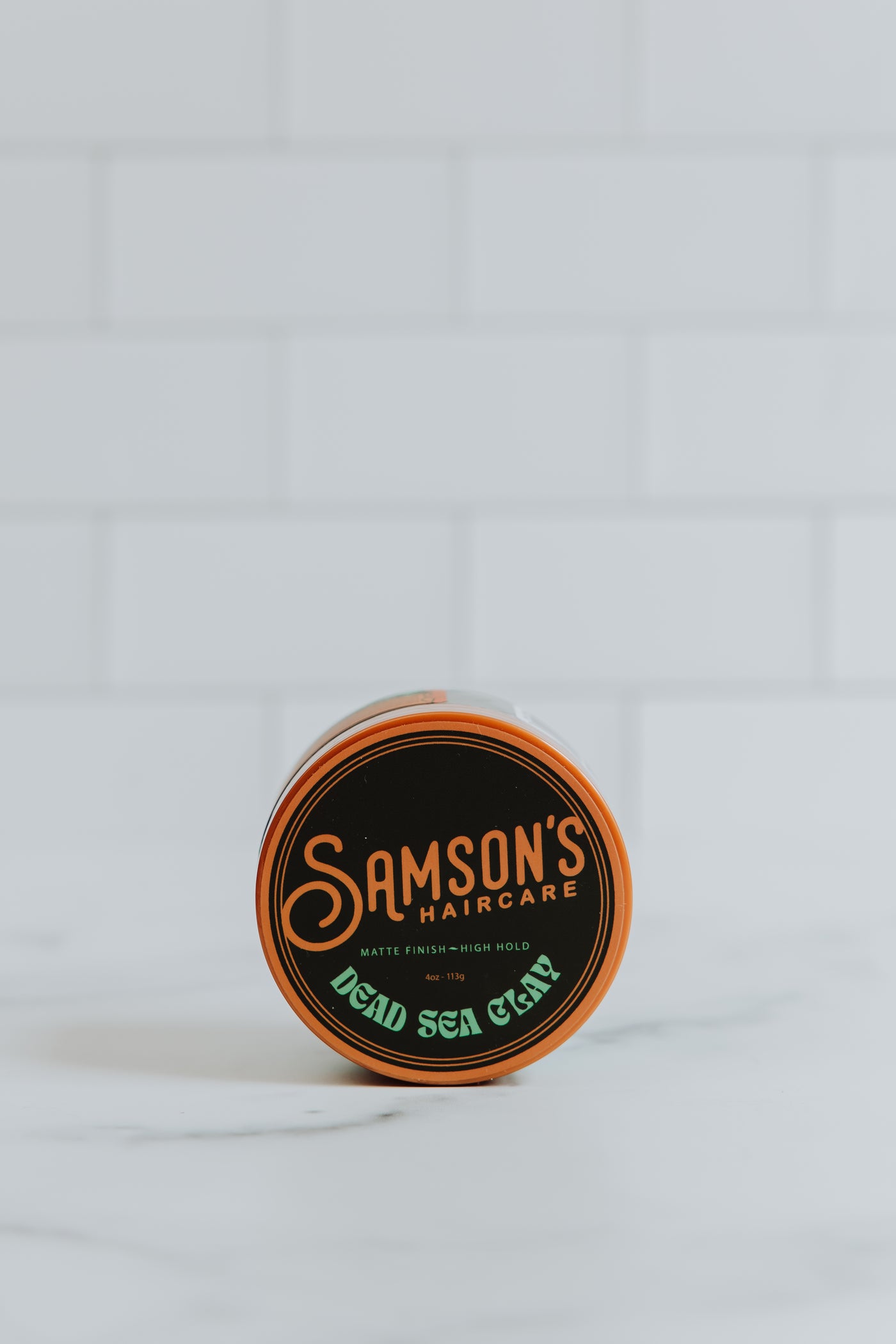 4 oz Dead Sea Clay on its side to showcase the top of the container against a white background.
