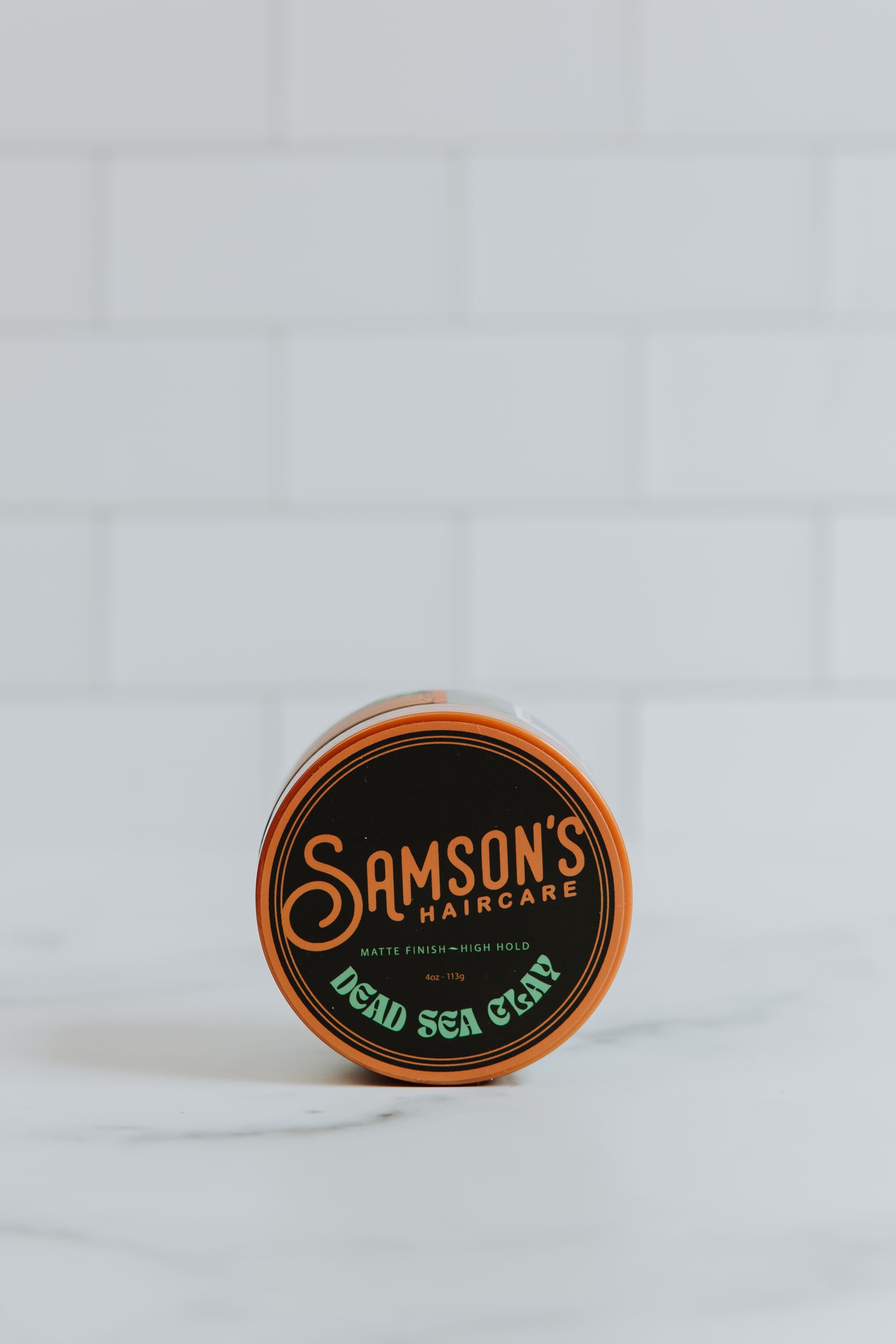 4 oz Dead Sea Clay on its side to showcase the top of the container against a white background.